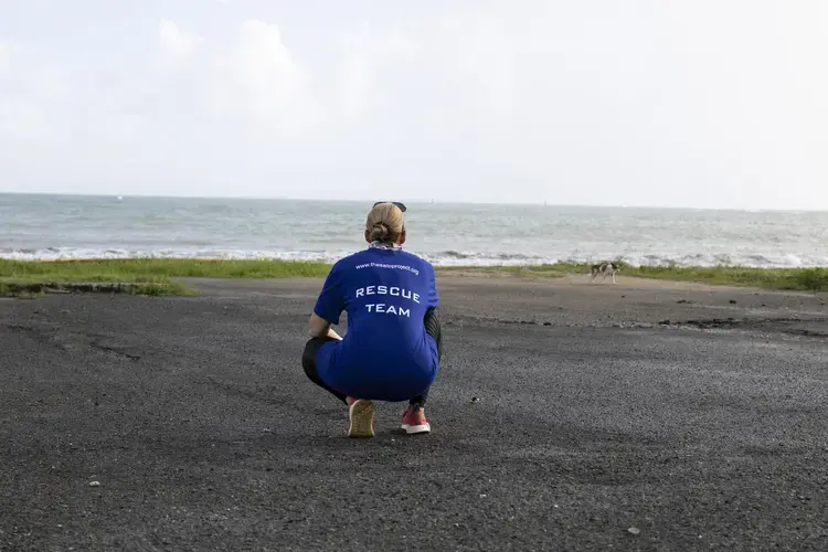 Beckles squats down in an attempt to draw a skittish dog closer. Image by Jamie Holt. United States, 2019.