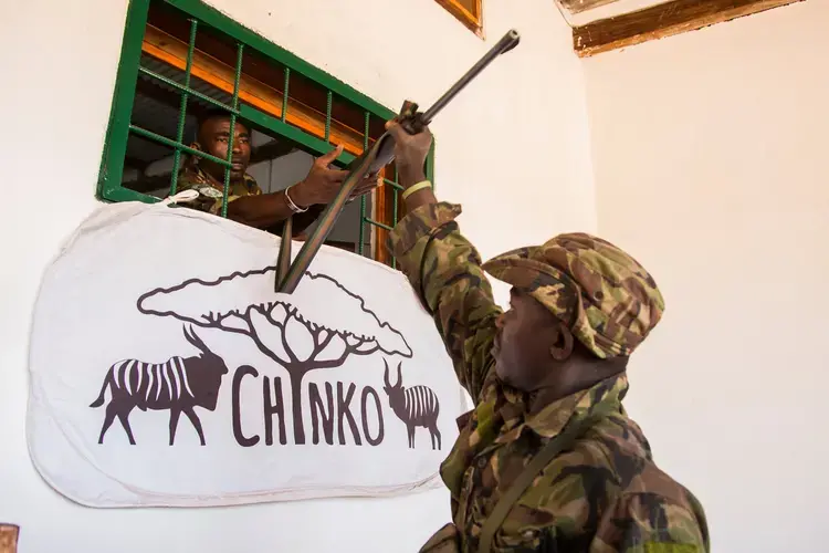 Dieudonné, a ranger, returns from patrol and hands his weapon over to senior ranger Saint-Cyr in Chinko’s armoury. Image by Jack Losh. Central African Republic, 2018.