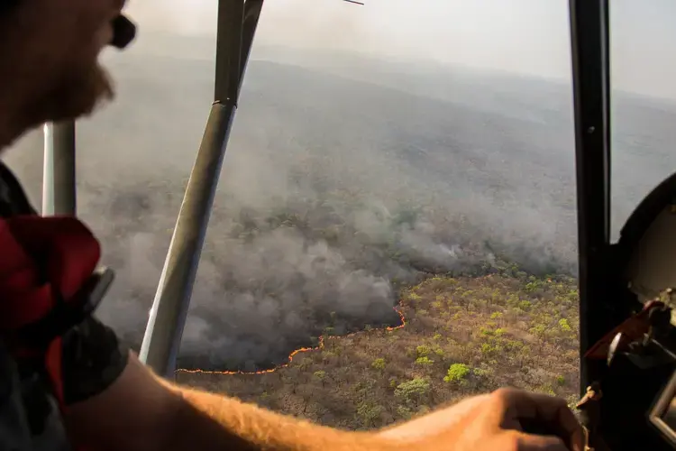 Cédric Ganière, one of the Chinko’s pilots, flies over a bushfire on the savannah in his tiny, two-seater plane during a mission to spot blazes lit by cattle herders. Image by Jack Losh. Central African Republic, 2018.
