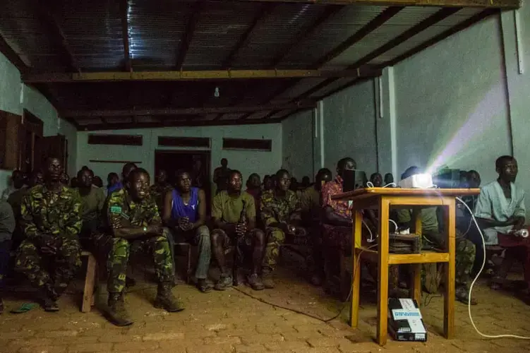 Rangers and other Chinko workers watch a French Ligue 1 football game projected onto a big screen at the end of the working day. Image by Jack Losh. Central African Republic, 2018.