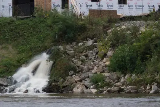 Stormwater runs into the lower Fox River in Wrightstown, southwest of the City of Green Bay. The river flows north to Green Bay. Nutrients in stormwater can spur algae growth that can lead to “dead zones” in the bay. Polluted runoff can come from cities and farms. Image by Mark Hoffman. United States, 2019.