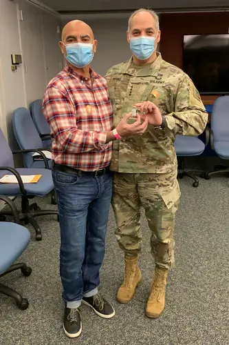 Moncef Slaoui (left) and Gen. Gustave Perna, co-leaders of Operation Warp Speed, hold a vial of COVID-19 vaccine on the day they both get vaccinated. Image courtesy of Moncef Slaoui. United States, 2021.