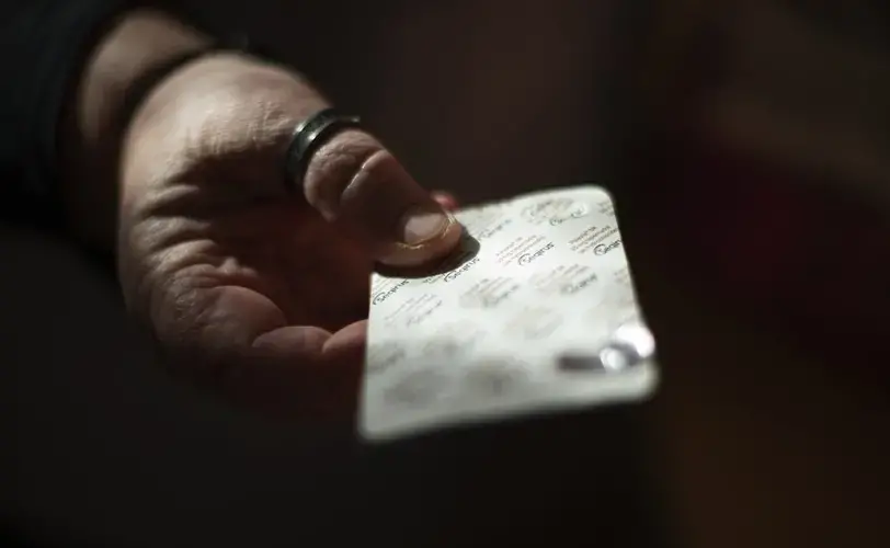 Carmall Casey finds an old pack of tapentadol while going through her box of medicine in her kitchen in Black River, Tasmania, Australia, Wednesday, July 24, 2019. Ten years ago, while working as a dairy farmer, Casey jumped off a truck and injured her knees. An operation provided temporary relief, but the pain came back. A doctor prescribed her opioids to ease her pain. When she stuck the first patch on her skin, it felt like heaven. Image by David Goldman. Australia, 2019.