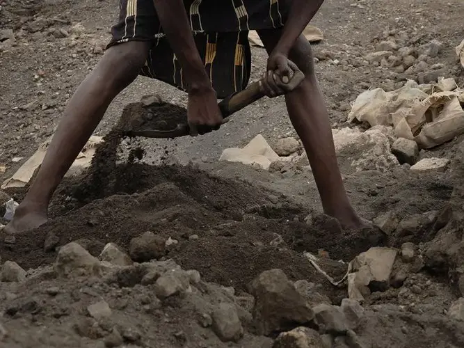 A miner digs through a layer of lead slag with a crude tool. Image by Larry C. Price. Zambia, 2017.