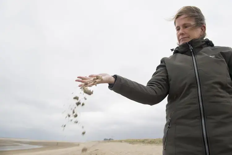 Carola van Gelder, program manager for the Sand Motor, lets sand fall between her fingers. Image by Chris Granger. Netherlands, 2019.