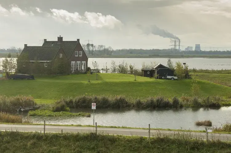 The few homes permitted to remain in the Noordwaard floodplain are on mounds surrounded by fields that regularly flood. Image by Chris Granger. Netherlands, 2019.
