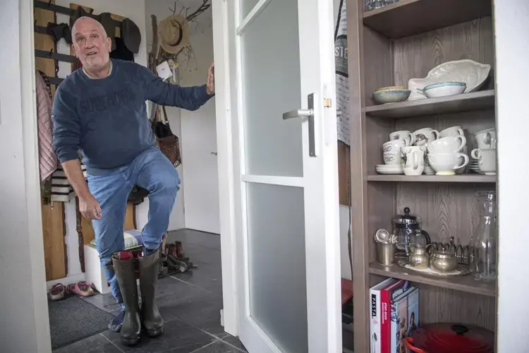 Vic Gremmer removes his boots as he walks into the house he built outside the Noordwaard floodplain in South Holland. Image by Chris Granger. Netherlands, 2019.
