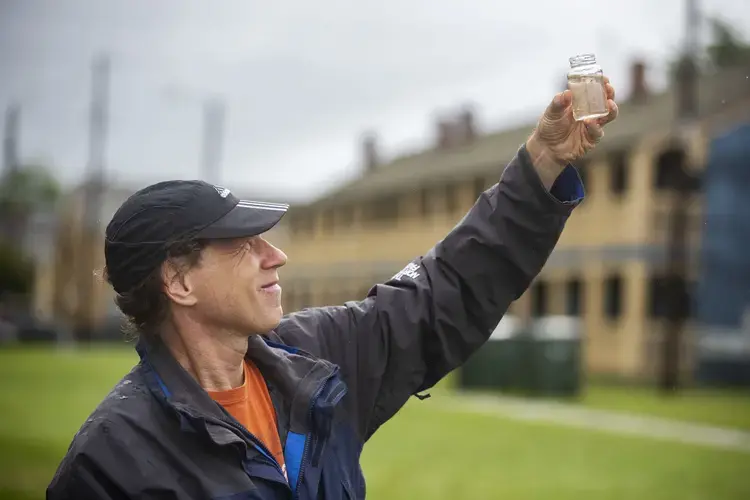 Tony Bartelme, projects reporter for The Post and Courier, collects a sample of floodwater from the intersection of Line and Flood Streets in downtown Charleston after a heavy rain on Wednesday, May 27, 2020. Image by Lauren Petracca / Post and Courier. United States, 2020.