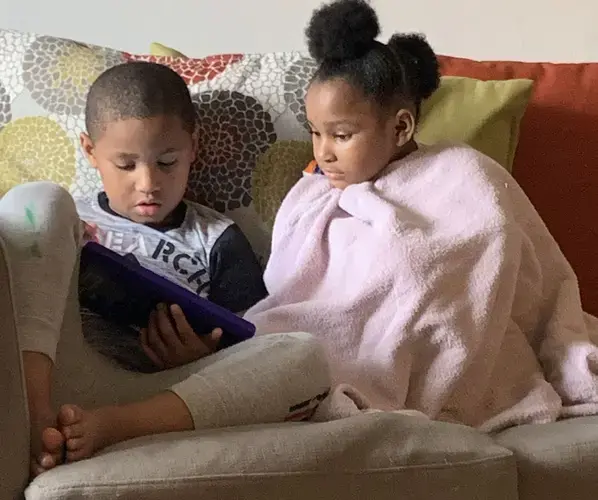 Meegale and Madison Hundley share a tablet to play an educational game during the pandemic. Image by Aisha Sultan / Post-Dispatch. United States, 2020.