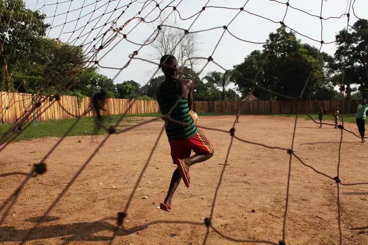 A 16-year-old boy who was a bodyguard in the opposition group South Sudan National Liberation Movement (SSNLM) plays football outside the transit centre ran by World Vision and UNI. Image by Andreea Campeanu. South Sudan, 2018.