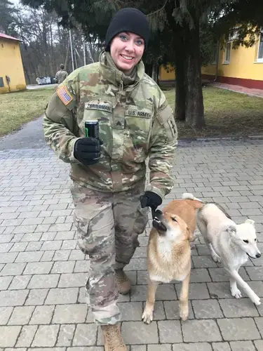 Sgt. Jamie Zimmerman plays with Max and Snowball at the International Peacekeeping and Security Centre in Yavoriv, Ukraine. Zimmerman is serving a one-year deployment as a Wisconsin National Guard medic but her civilian job is veterinarian. Image by Meg Jones / Milwaukee Journal Sentinel. Ukraine, 2020.