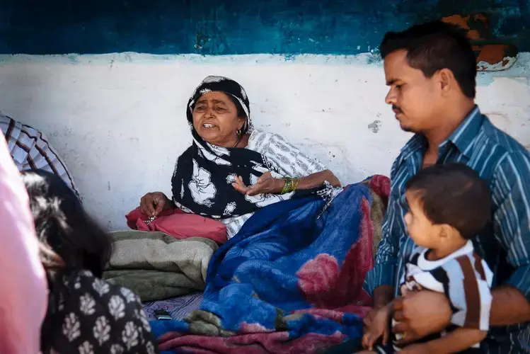 Munni bi lies on her bed outside her house in Annu Nagar. Image by Raj Sarma. India, 2018.