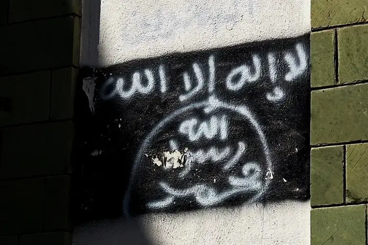 The black al-Qaida flag is sprayed on the wall of a damaged school in Taiz. Image by AP. Yemen, 2017.