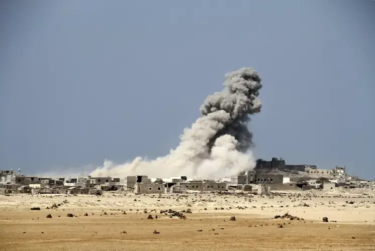 An explosion raises a cloud as coalition-backed fighters advance on the Red Sea port town of Mocha. Image by AP. Yemen, 2017.</p>
<p>