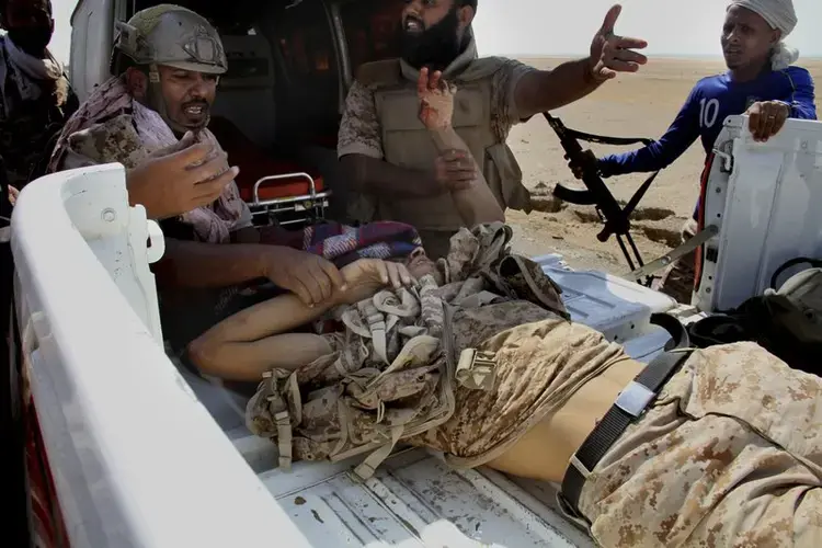 Coalition-backed fighters help a wounded man during an advance on Yemen’s Red Sea port town of Mocha. Image by AP. Yemen, 2017.