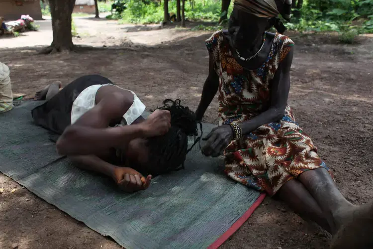 An older woman with a family member at her home in Yambio. She welcomed three of her granddaughters who were kidnapped and held by a rebel group into her home. Image by Andreea Campeanu. South Sudan, 2018.