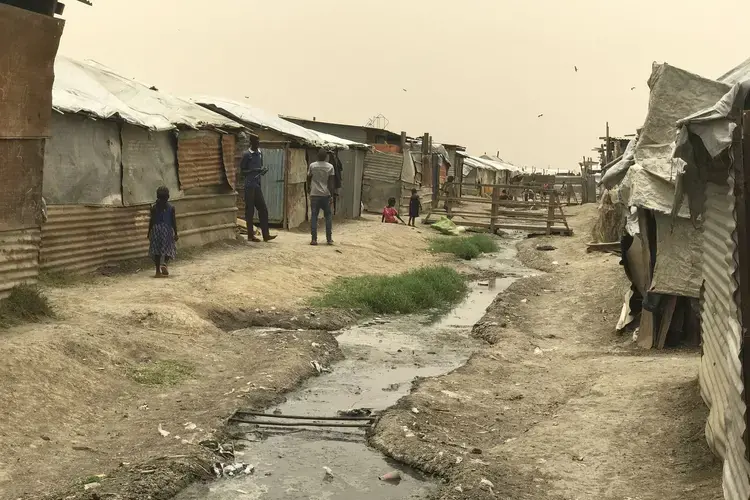 Sewage runs between shacks in Malakal Protection of Civilians site, a guarded camp for people fleeing tribal violence in South Sudan. Image by Jane Ferguson. South Sudan, 2017.