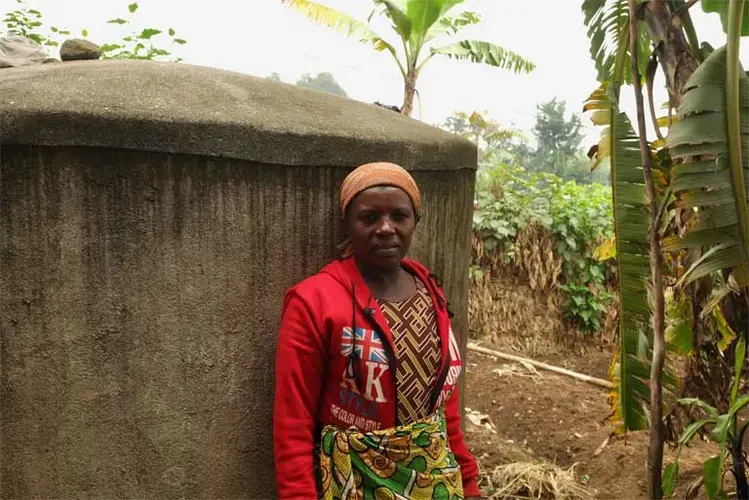 Farmers living near Volcanoes National Park face decreased access to clean water due to intense drought, a result of climate change. Vestine Mukanoheri, a farmer from the Gahunga Sector, manages her household needs using a home water tank provided by the International Gorilla Conservation Programme. However, many farmers must travel into the national park to find potable water. Image by Elham Shabahat. Rwanda, 2017.