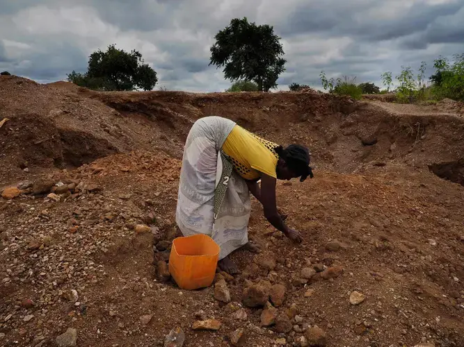 Elsewhere on the contaminated former mine site, women and children crush rock to sell as gravel. Image by Larry C. Price. Zambia, 2017.