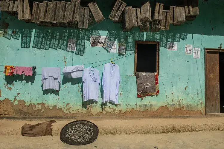 Fish, clothes, and traditional bamboo fish traps sit outside the home of the Leishram family in the village of Thanga in Manipur. Fishing remains the primary livelihood of over 30,000 people in the communities surrounding the lake. Image by Neeta Satam. India, 2017.