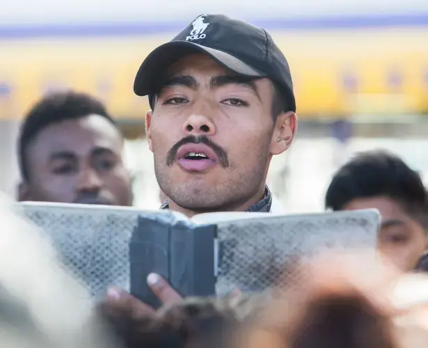 In November 2018, Yovani, a migrant from Michoacán, reads aloud the names of asylum seekers who will be interviewed by U.S. Customs and Border Protection officials in Tijuana that day. Image by Omar Ornelas/The Desert Sun. Mexico, 2018.