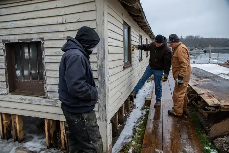 James Keighley, center, owner of Patrick's Landing, talks to Mark Engle, right, owner of the nearby Les Cheneaux Landing resort, and Chad Cortes, of North Shore Docks, on Nov. 20, 2019. Cortes and his workers are rebuilding docks at Patrick's Landing. Image by Zbigniew Bzdak / Chicago Tribune. United States, 2020.