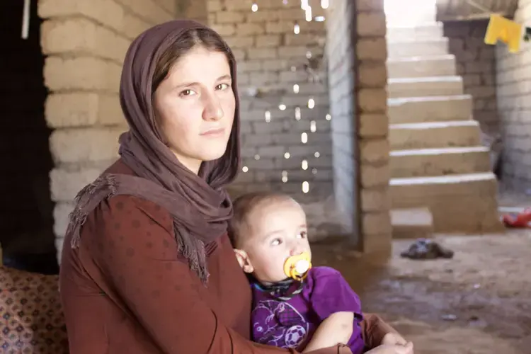 Amsha Ali Alyas holds her son Muiad in her lap at her parent’s home outside of the Iraqi city of Duhok days after she escaped from ISIS captivity in the summer of 2014. Image by Emily Feldman. Iraq, 2014.