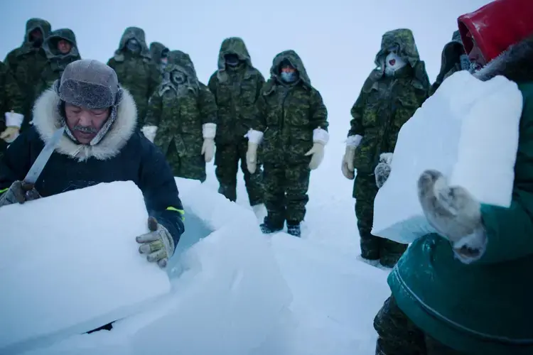 In the frigid temperatures of the High Arctic, survival means finding shelter—or making your own. Here, at a survival course held at the Crystal City training facility on Resolute Bay on the Northwest Passage, Inuit instructors Jolie Qaunaq (left) and Andy Issigaitok teach soldiers and pilots from Canada, the United Kingdom, and France how to build an iglu from blocks of snow. Image by Louie Palu. Canada, 2018.