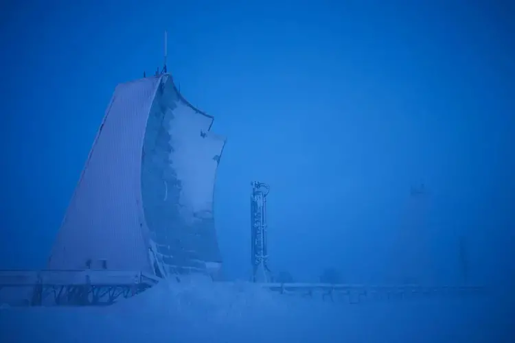 A long-range radar installation rears up from the tundra in Hall Beach, Nunavut, Canada. The radar is one of 50 unmanned surveillance stations that keep watch over North America’s northern frontier, stretching from Canada’s eastern coast to the west coast of Alaska. Called the North Warning System, the radar line is jointly operated by Canadian and U.S. forces under NORAD, the North American Aerospace Defense Command. Image by Louie Palu. Canada, 2018.