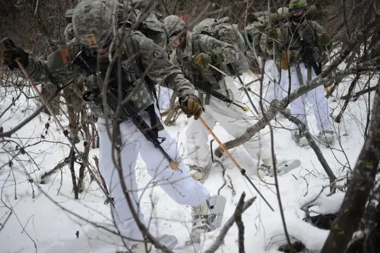 Thick brush, deep snow, and unfamiliar gear, including snowshoes and bulky “Mickey Mouse” boots—so called because they resemble the feet of the famous Disney character—conspire against U.S. soldiers training for Arctic battles at the Northern Warfare Training Center. Image by Louie Palu. United States, 2018.