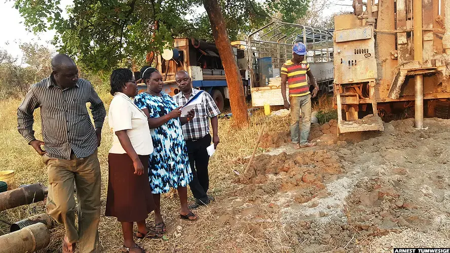 District staff of Omoro at a site where a borehole was being drilled. Image by Arnest Tumwesige. Uganda, 2020.
