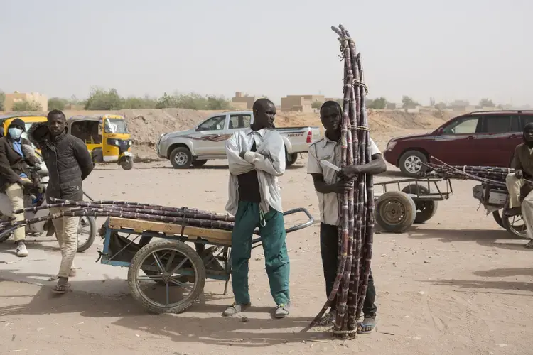 Sugarcane vendors stand outside during a ceremony at a police station in Agadez, Niger, Jan. 15, 2018. Image by Joe Penney. Niger, 2018.