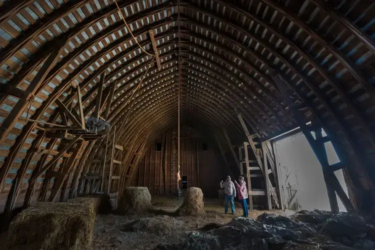 Bruce Drinkman and his companion, Betty Jo Johnson, stand in the hayloft designed to hold about 10,000 bales of hay at the farm in Ridgeland. Drinkman, a former dairy farmer, purchased this small farm in Dunn County. Image by Mark Hoffman. United States, 2019.