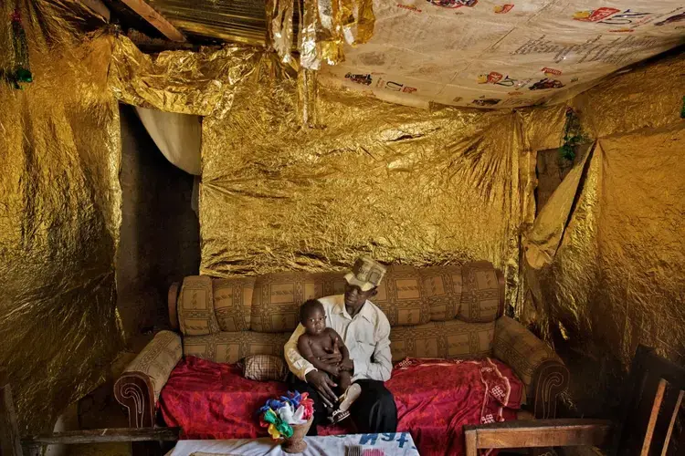 After a year in a camp, Richard Dohou celebrated his return home by decorating with gold paper. His Bangui neighborhood, once a vibrant mix of Muslims and Christians, was emptied by brutal killings. Christians like Dohou are returning, but Muslims are not. “We can forgive each other someday,” says a resident, “but not yet.” Image by Marcus Bleasdale. Central African Republic.