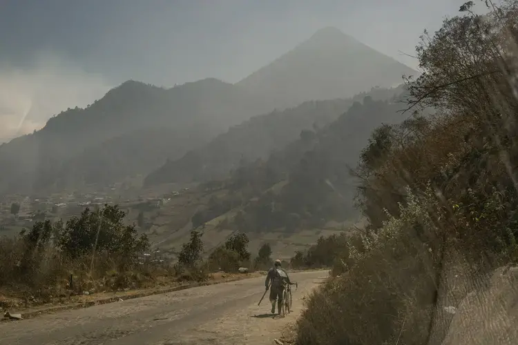 A villager walks along a road down the Siete Orejas mountain, outside the village of Xecaracoj, with the Santa María volcano in the background. Image by Mauricio Lima. Guatemala, 2019.