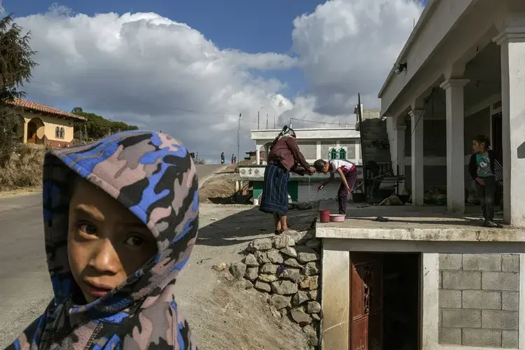 A mother washes her daughter’s hair outside their house, which was built with remittance money. Image by Mauricio Lima. Guatemala, 2019.