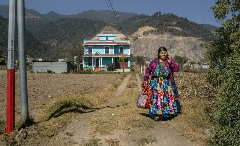 A Maya woman outside her home, which was funded by remittances from a relative living in the United States. Image by Mauricio Lima. Guatemala, 2019.<br />
