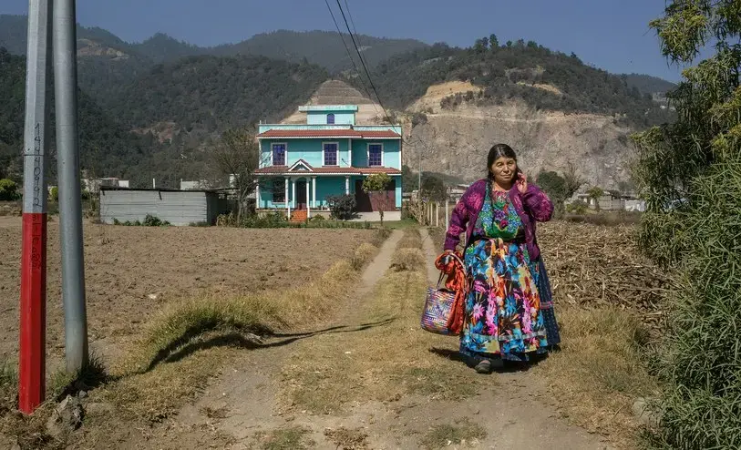 A Maya woman outside her home, which was funded by remittances from a relative living in the United States. Image by Mauricio Lima. Guatemala, 2019.<br />