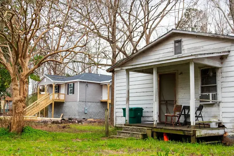 A hurricane and flood damaged home next to a repaired home in Sellers, South Carolina, on February 13, 2020. Homeowners with a clear title and insurance have rebuilt their homes in Sellers, many homeowners have not received disaster assistance and live with mold and leaks. Image by Joshua Boucher. United States, 2020.