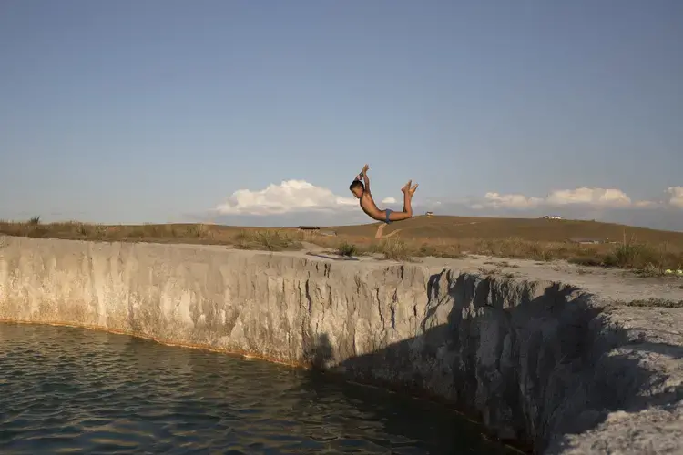 A Pemón youngster plunges into a turquoise-colored settling pond at the Campo Alegre mining site in the state of Bolívar. Image by Fabiola Ferrero. Venezuela, 2020.