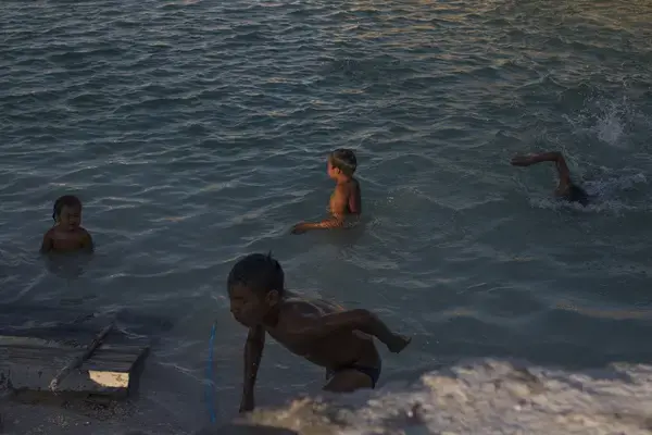 A group of children cooling off in the settling ponds at the mining area, a couple of hours after the school day is over. Image by Fabiola Ferrero. Venezuela, 2020.