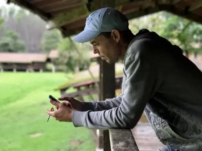 Liuber Pérez Expósito spends a lot of time on his cell phone with family in Cuba while he waits at a camp in Gualaca, Panama for a decision on his fate. Image by Mario J. Pentón. Panama, 2017.