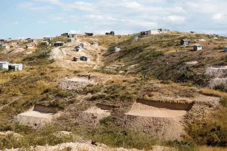 A man works to level a plot of land in order to begin building a home in the Canaan settlement, just outside of Port-au-Prince. Image by Allison Shelley. Haiti, 2017.<br />
