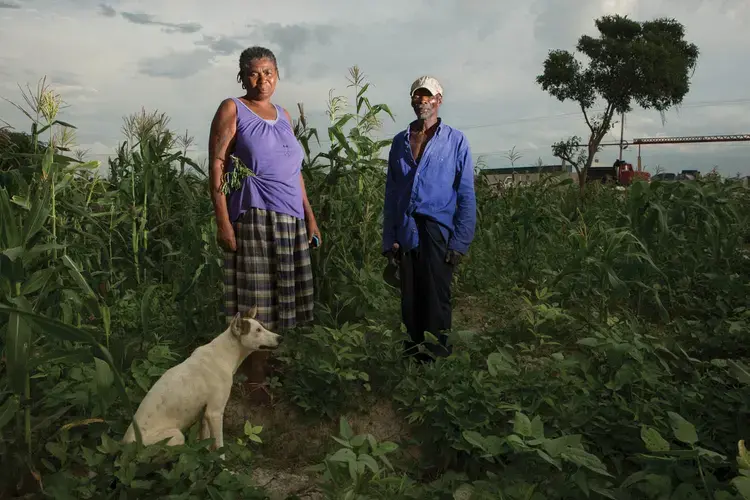 Jean Leon and her husband, Michelet Alexandre, in their field near Corail. They arrived in 1996, when there were only three families in the area. Now their property, where they grow crops and raise cattle, is surrounded by a fast-developing neighborhood. “We came from the countryside to find life, and we certainly found life,” says Leon. Image by Allison Shelley. Haiti, 2017.