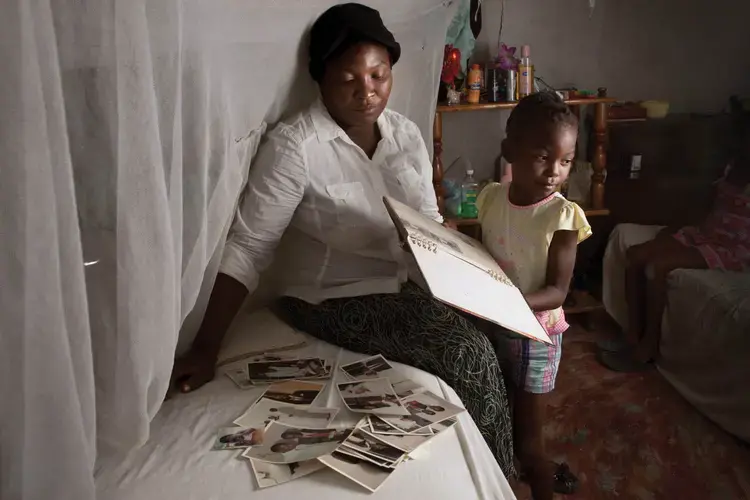 Magalie Gabriel, the widow of Smith Merzeus, with their daughter, Rachel. Merzeus was assassinated in a drive-by shooting outside their home in Canaan 5. Image by Allison Shelley. Haiti, 2017.<br />
