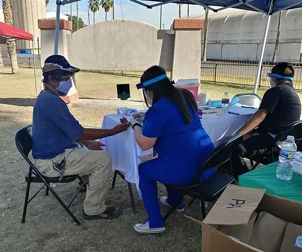 A homeless man is tested for COVID-19 by a medical assistant from Calexico Wellness Center at the Brown Bag Coalition’s health clinic in Calexico, California, on May 7. Image courtesy of Brown Bag Coalition. United States, 2020.