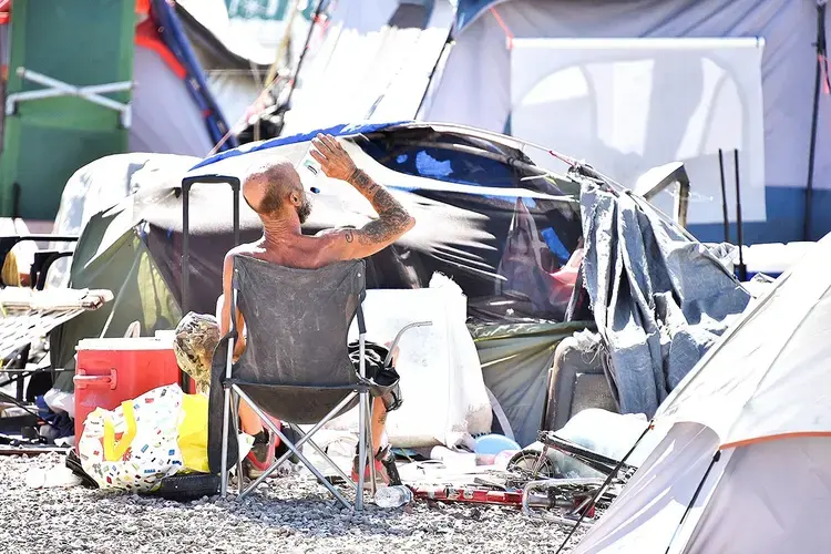 A homeless man sits by his belongings at the Lots, an outdoor encampment in Phoenix, on June 24. Summer temperatures in Phoenix consistently exceeded 110 degrees Fahrenheit, sometimes hitting 118. Image by Steve Carr/Human Services Campus. United States, 2020.<br />
