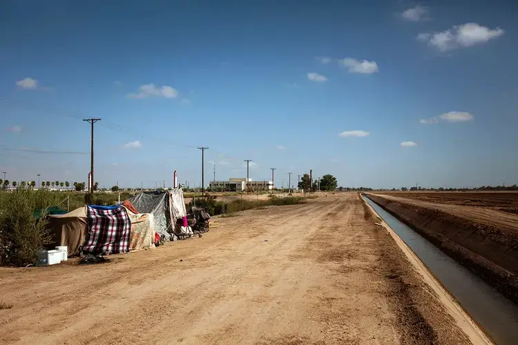 A homeless encampment near a canal in El Centro, Calif., as seen on July 24, 2020. As support services have dwindled amid the COVID-19 pandemic, some homeless people in Imperial County have resorted to bathing in irrigation canals. Homelessness looks different in different parts of the U.S., especially in rural agricultural regions such as Imperial County. Image by Anna Maria Barry-Jester/KHN. United States, 2020.<br />
