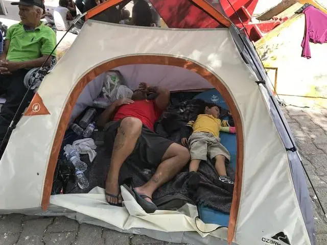 A man and a child sleep in a small tent pitched on the Matamoros, Mexico, side of the Gateway International Bridge that Connects Matamoros to Brownsville, Texas. Image by Jose A. Iglesias. Mexico, 2019.