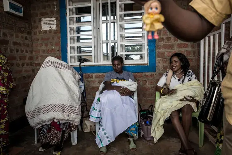 Three women who have recently been cured of Ebola wait with their children for medical checks at a treatment centre in Beni. Beni, Democratic Republic of the Congo. Image by John Wessels.